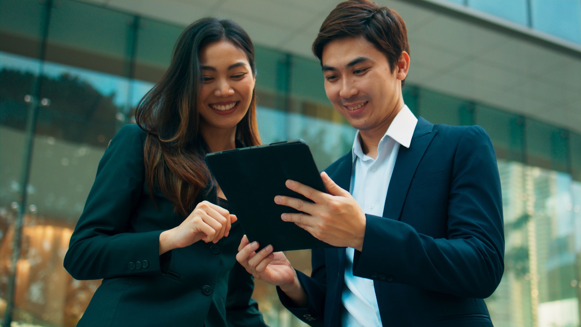 Professional young Asian business people team using digital tablet, consulting, discussing financial market plan and working in modern office building